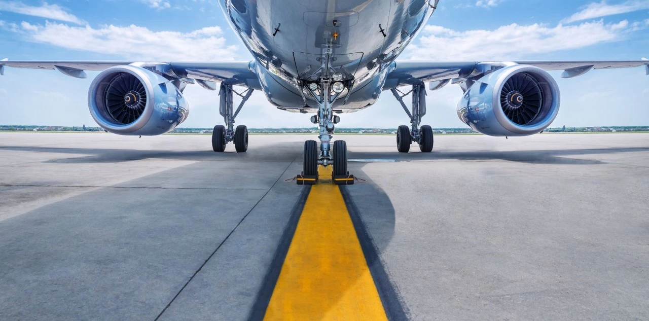 Imagem ilustrativa de um avião estacionado na linha amarela da pista do aeroporto